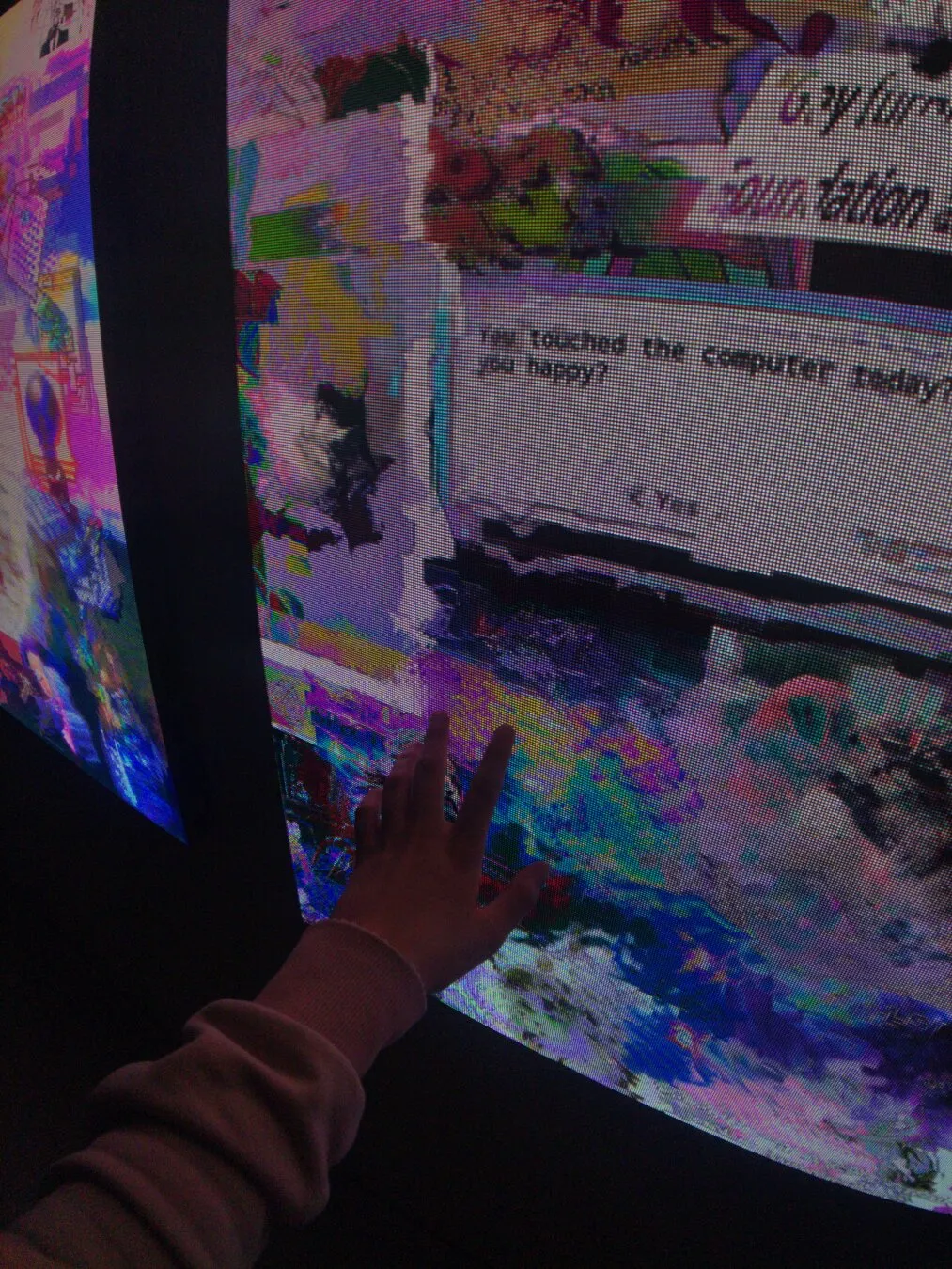 my hand reaching out to touch my artwork computer_downloads_folder.jpg, that contains an old dos style button asking "you touched the computer today, did it make you happy? yes/no"